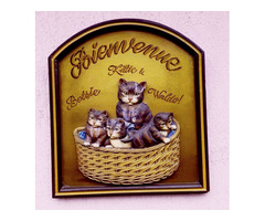 Domborműves üdvözlő reklámtábla cicákkal, keretezve.